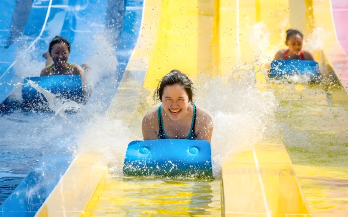 Water slides at Escape Penang water park with people enjoying the ride.