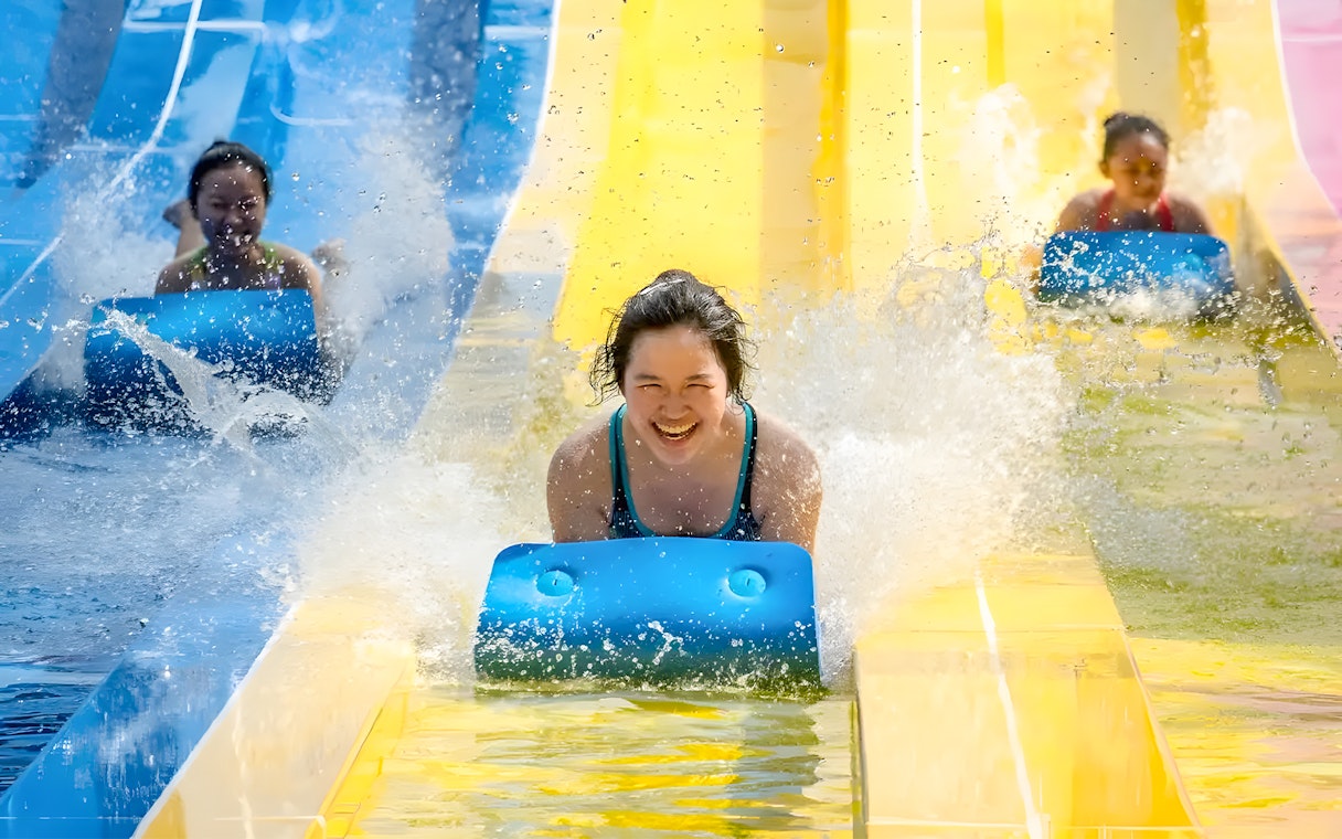 Water slides at Escape Penang water park with people enjoying the ride.