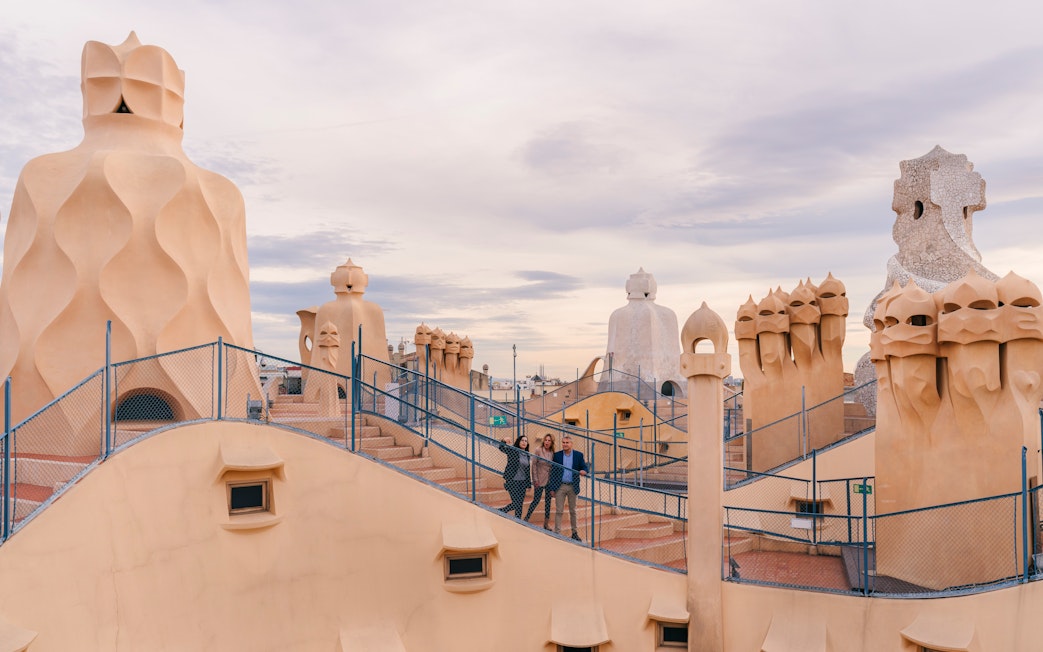 Tourists with guide on Casa Mila rooftop, exploring unique chimneys in Barcelona.