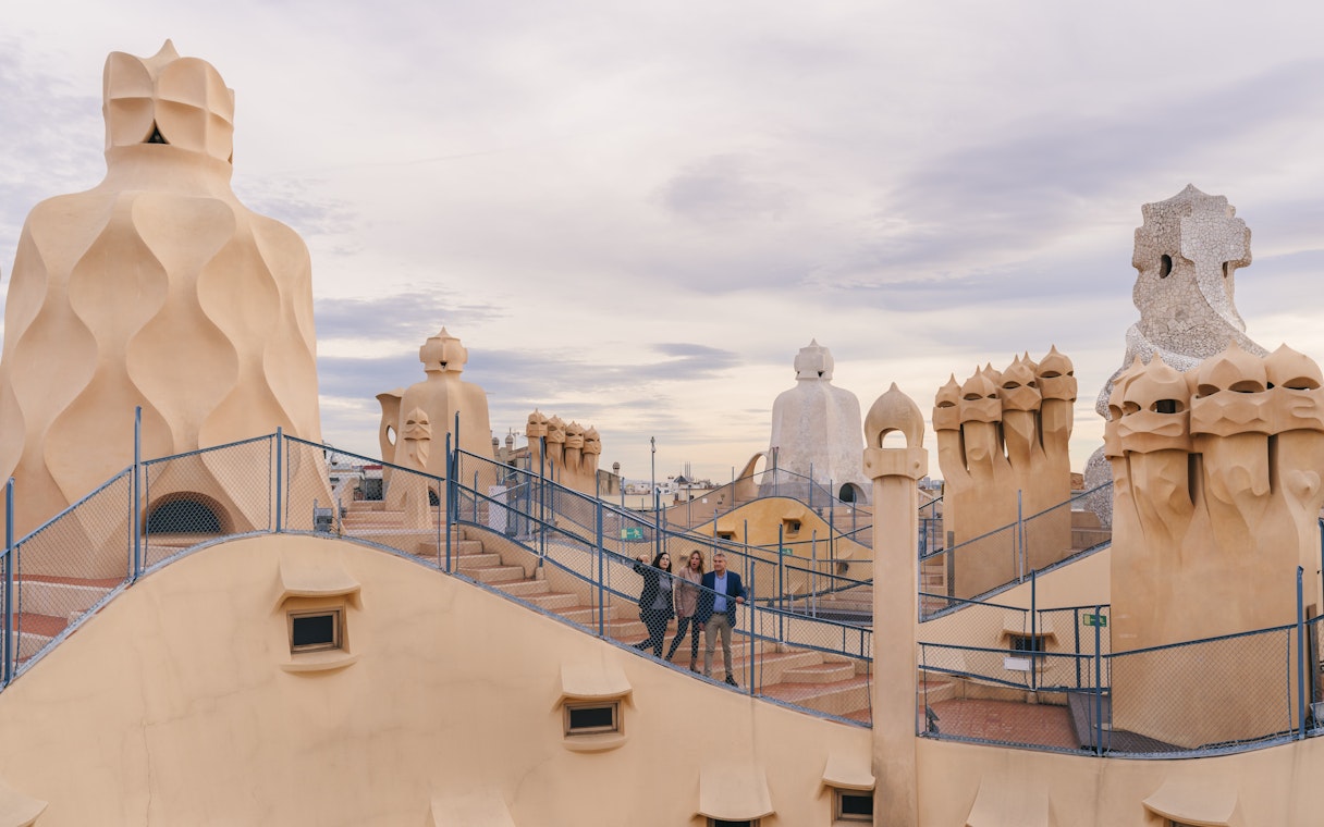 Tourists with guide on Casa Mila rooftop, exploring unique chimneys in Barcelona.