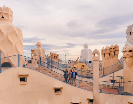 Tourists with guide on Casa Mila rooftop, exploring unique chimneys in Barcelona.