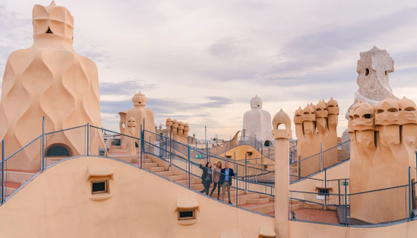 Tourists with guide on Casa Mila rooftop, exploring unique chimneys in Barcelona.