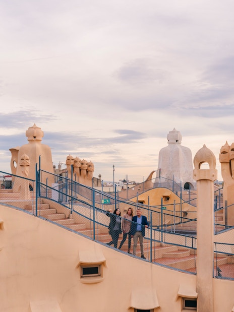 Tourists with guide on Casa Mila rooftop, exploring unique chimneys in Barcelona.