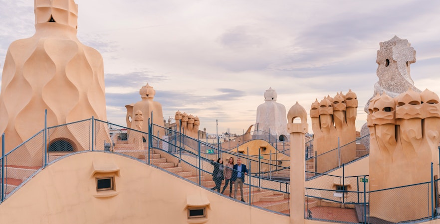 Tourists with guide on Casa Mila rooftop, exploring unique chimneys in Barcelona.