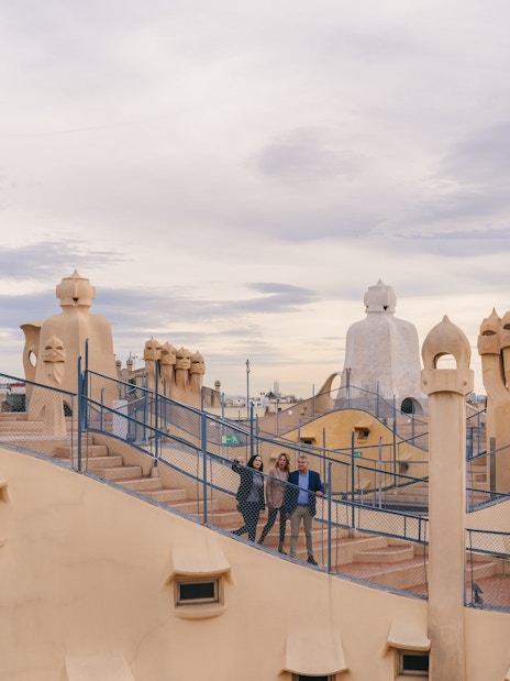 Tourists with guide on Casa Mila rooftop, exploring unique chimneys in Barcelona.