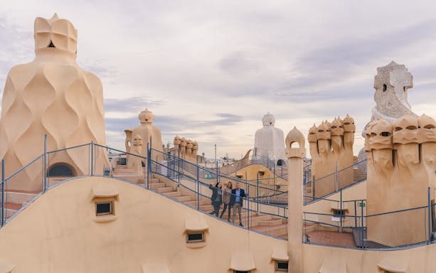 Tourists with guide on Casa Mila rooftop, exploring unique chimneys in Barcelona.