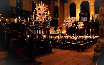 Interior of a historic synagogue with chandeliers and wooden pews, part of a Jewish history tour.