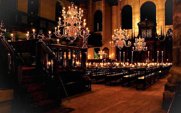 Interior of a historic synagogue with chandeliers and wooden pews, part of a Jewish history tour.
