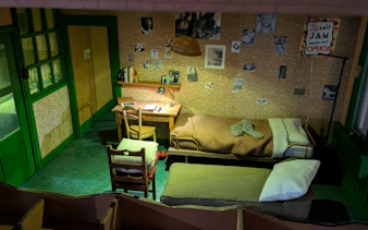Anne Frank's room replica with desk, bed, and wall photos in Amsterdam museum.