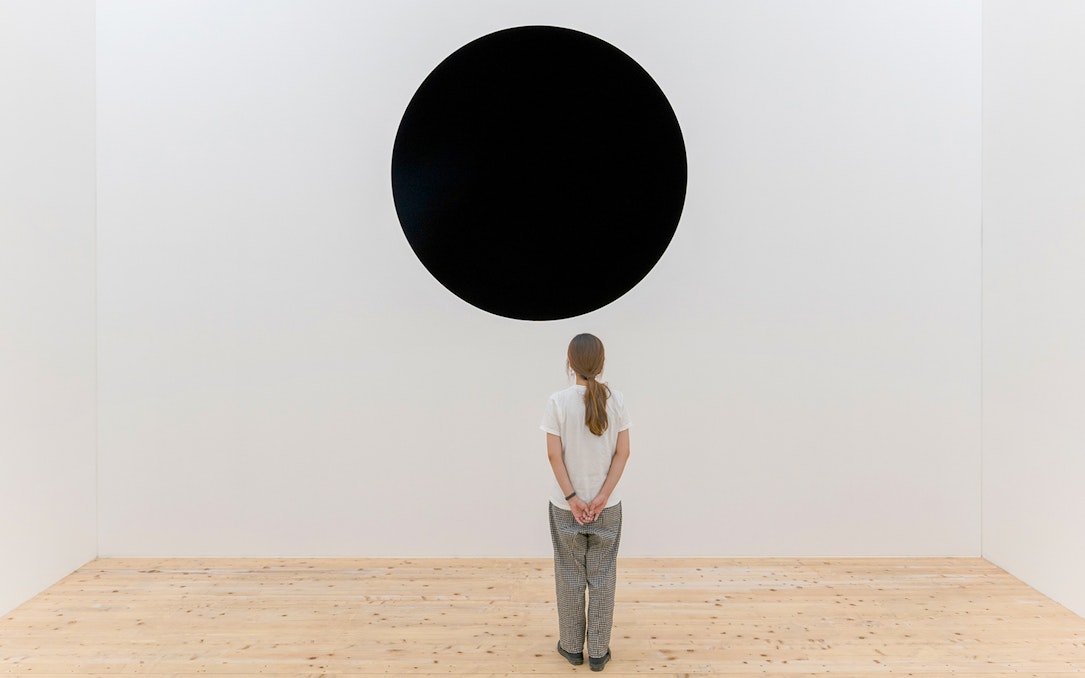 Person viewing Anish Kapoor's "Untrue Unreal" black circle installation.