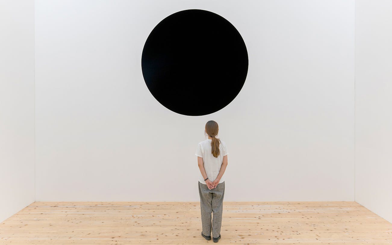 Person viewing Anish Kapoor's "Untrue Unreal" black circle installation.