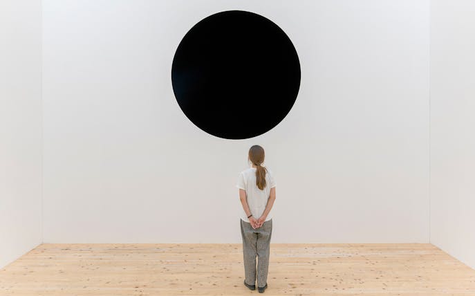 Person viewing Anish Kapoor's "Untrue Unreal" black circle installation.