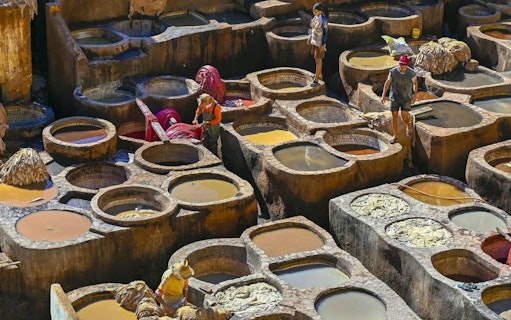 Tannery workers in Fes, Morocco, dyeing leather in stone vats.