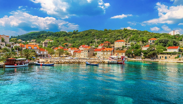 Boat tour approaching Elaphiti Island of Sipan, Dubrovnik, Croatia, with passengers enjoying the view.