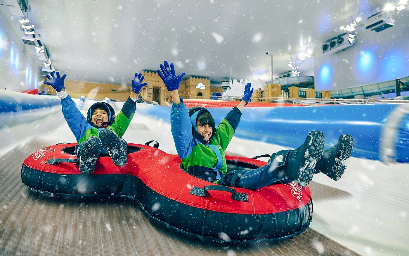 Children tubing down a snowy slide at Snow Dunes Theme Park.