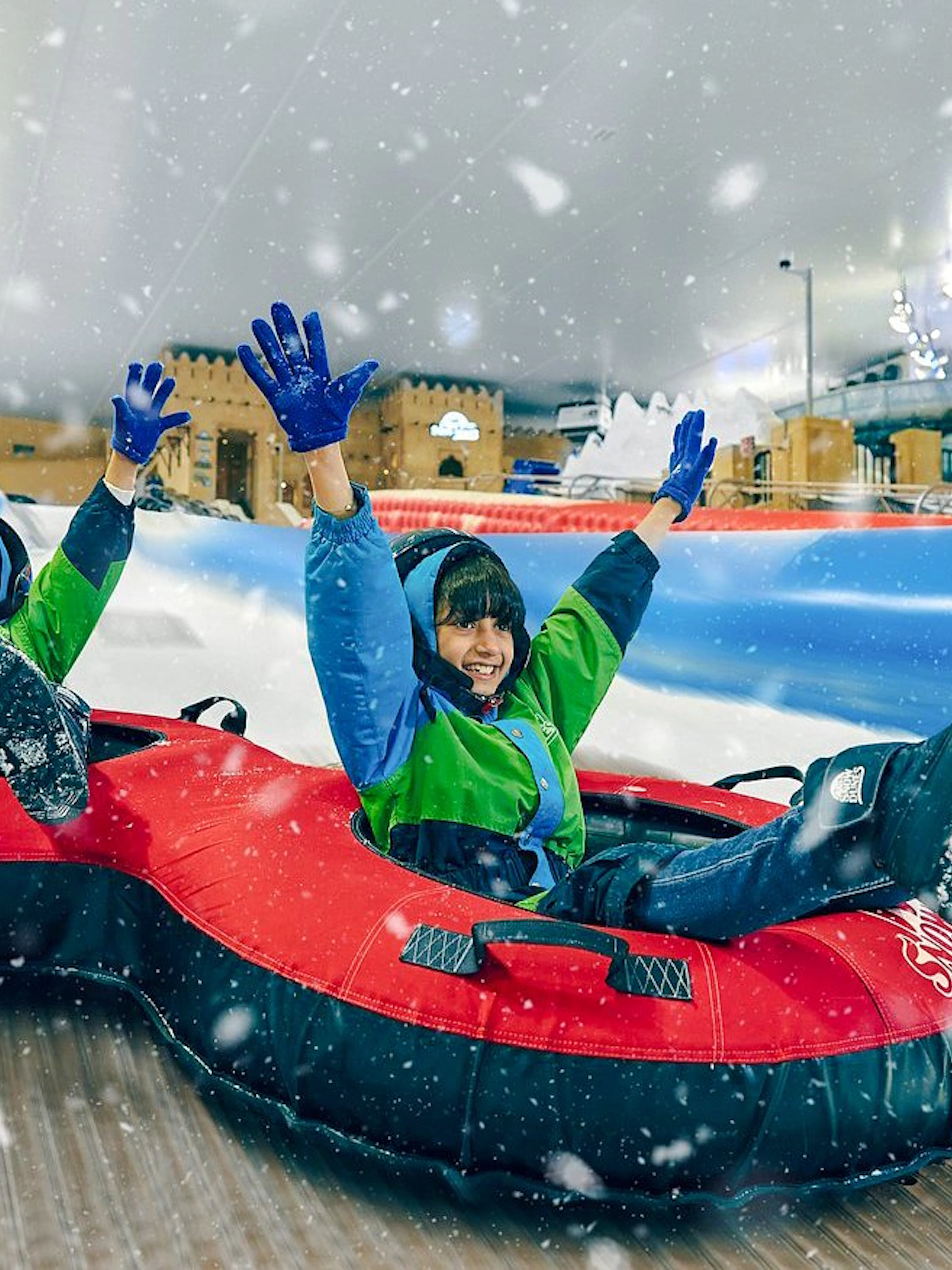 Children tubing down a snowy slide at Snow Dunes Theme Park.