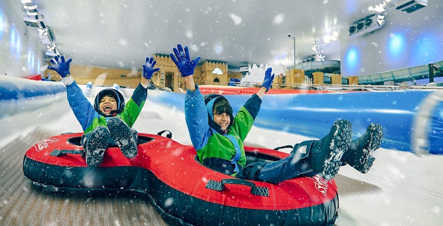 Children tubing down a snowy slide at Snow Dunes Theme Park.