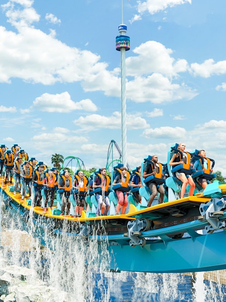 Roller coaster ride with people at an amusement park, blue sky background.