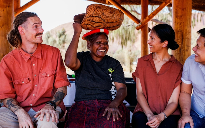 Aboriginal guide sharing stories with tourists during Uluru sunrise tour.