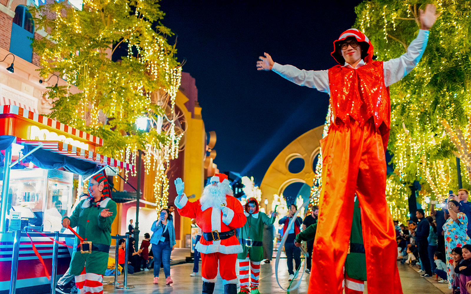 Festive performers and Santa at MOTIONGATE™ Dubai during a nighttime event.