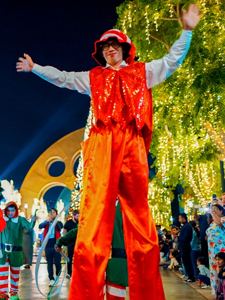 Festive performers and Santa at MOTIONGATE™ Dubai during a nighttime event.