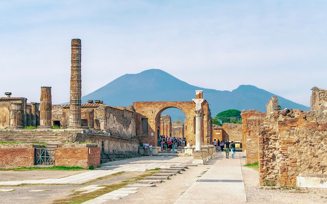 Ancient ruins of Pompeii with Mount Vesuvius in the background.