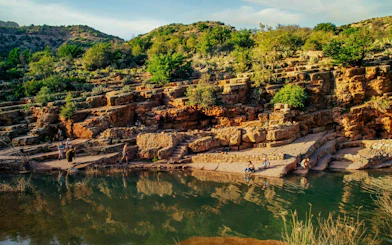 Rocky landscape with visitors by a river in Paradise Valley, surrounded by greenery and hills.
