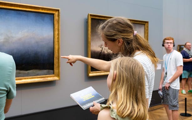Visitors observing paintings at Neues Museum, Berlin.