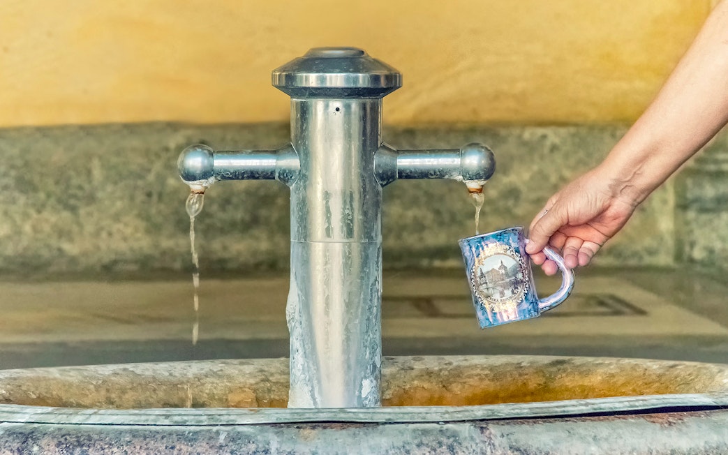 Filling a mug with mineral water from a spring in Karlovy Vary, Czech Republic.