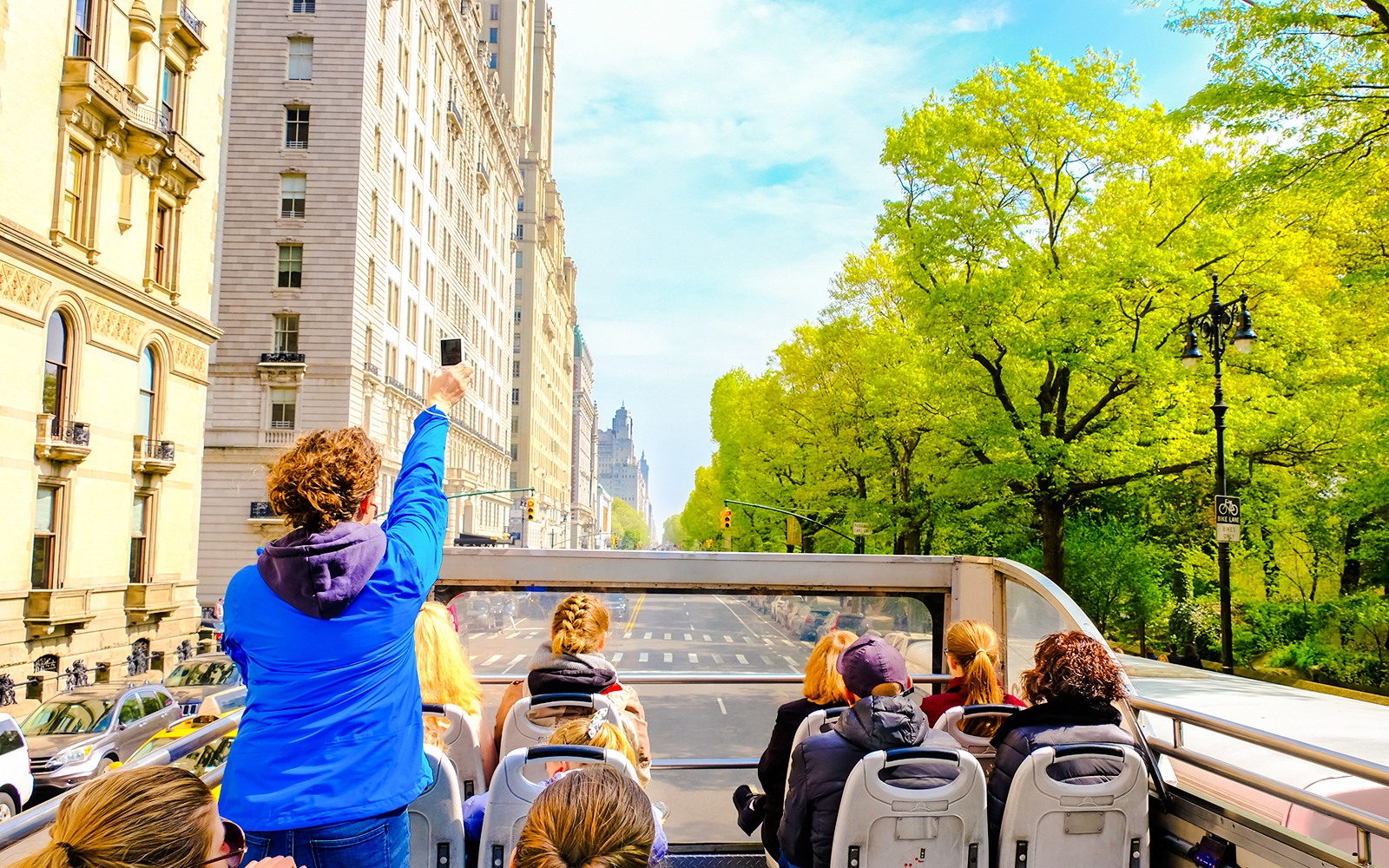 Open-top bus tour through New York City streets with passengers enjoying views.