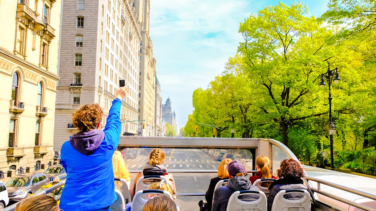 Open-top bus tour through New York City streets with passengers enjoying views.