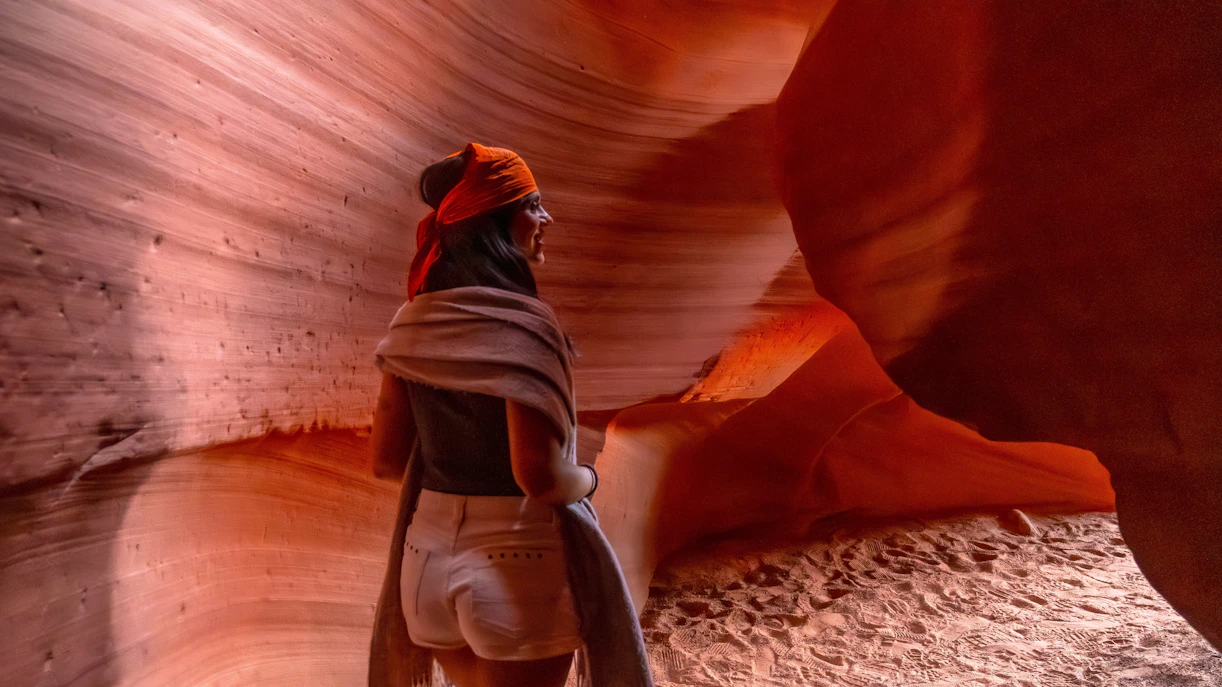 Woman walking through Antelope Canyon's narrow sandstone walls.