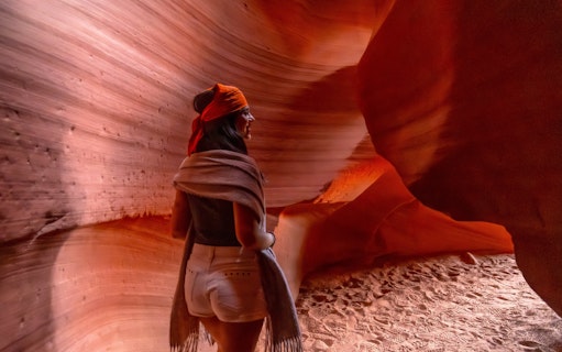 Woman walking through Antelope Canyon's narrow sandstone walls.