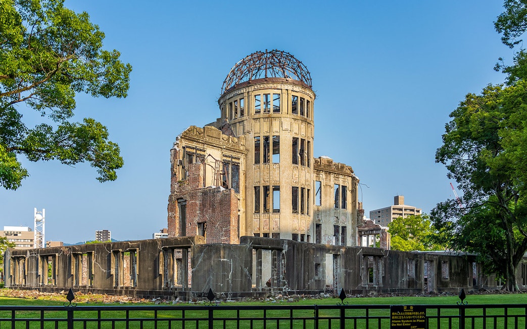 Atomic Bomb Dome at Hiroshima Peace Memorial Park, surrounded by trees and cityscape.