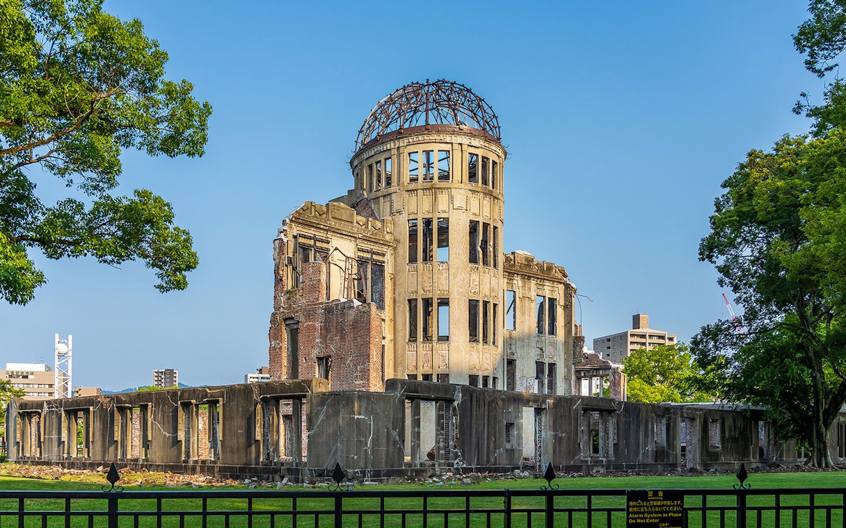 Atomic Bomb Dome at Hiroshima Peace Memorial Park, surrounded by trees and cityscape.