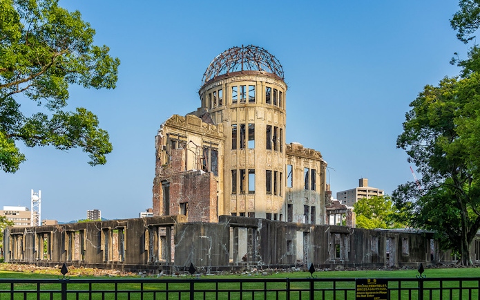 Atomic Bomb Dome at Hiroshima Peace Memorial Park, surrounded by trees and cityscape.