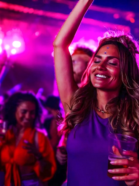 Tourists dancing and enjoying a vibrant party with colorful lights.