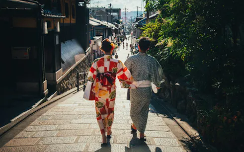 Two people in traditional kimonos walking down a street in Kyoto.