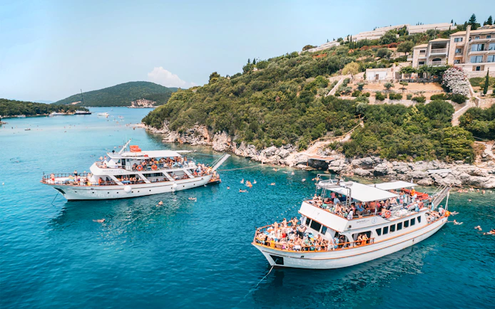 Cruise boats in Blue Lagoon near Papanikolis Cave, Benitses/Lefkimmi, with tourists swimming.