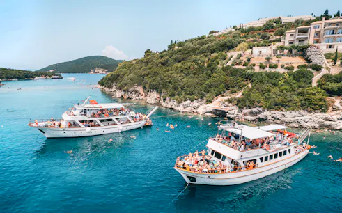 Cruise boats in Blue Lagoon near Papanikolis Cave, Benitses/Lefkimmi, with tourists swimming.