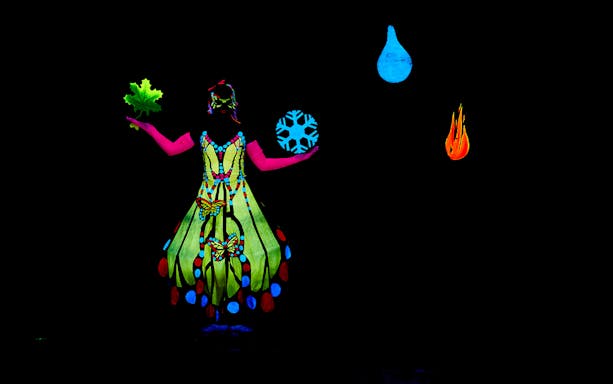 Performer in neon costume at WOW Show Black Light Theater, Prague.