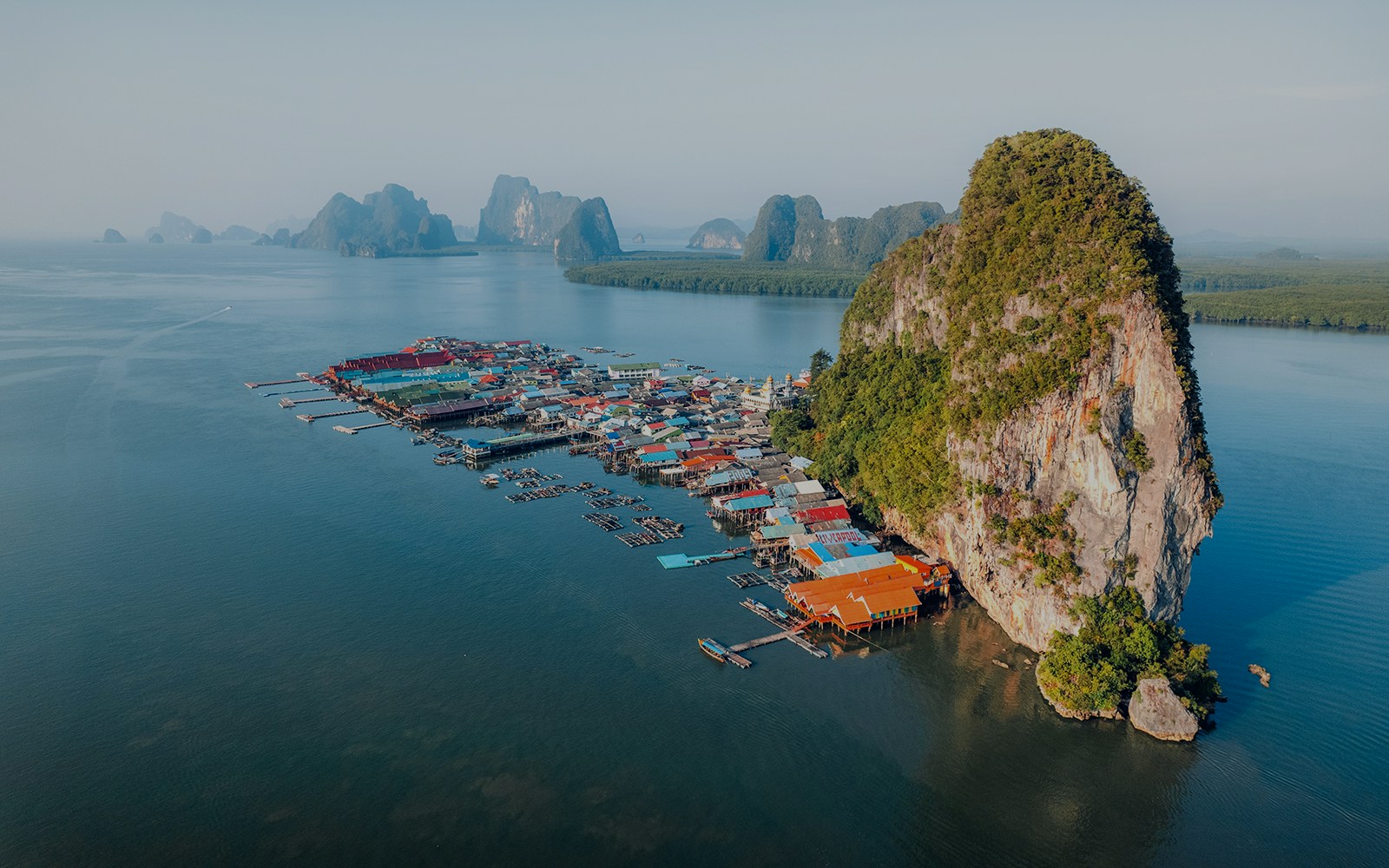 Floating village near limestone cliffs in Phang Bay, Thailand, seen on a speedboat tour from Phuket.
