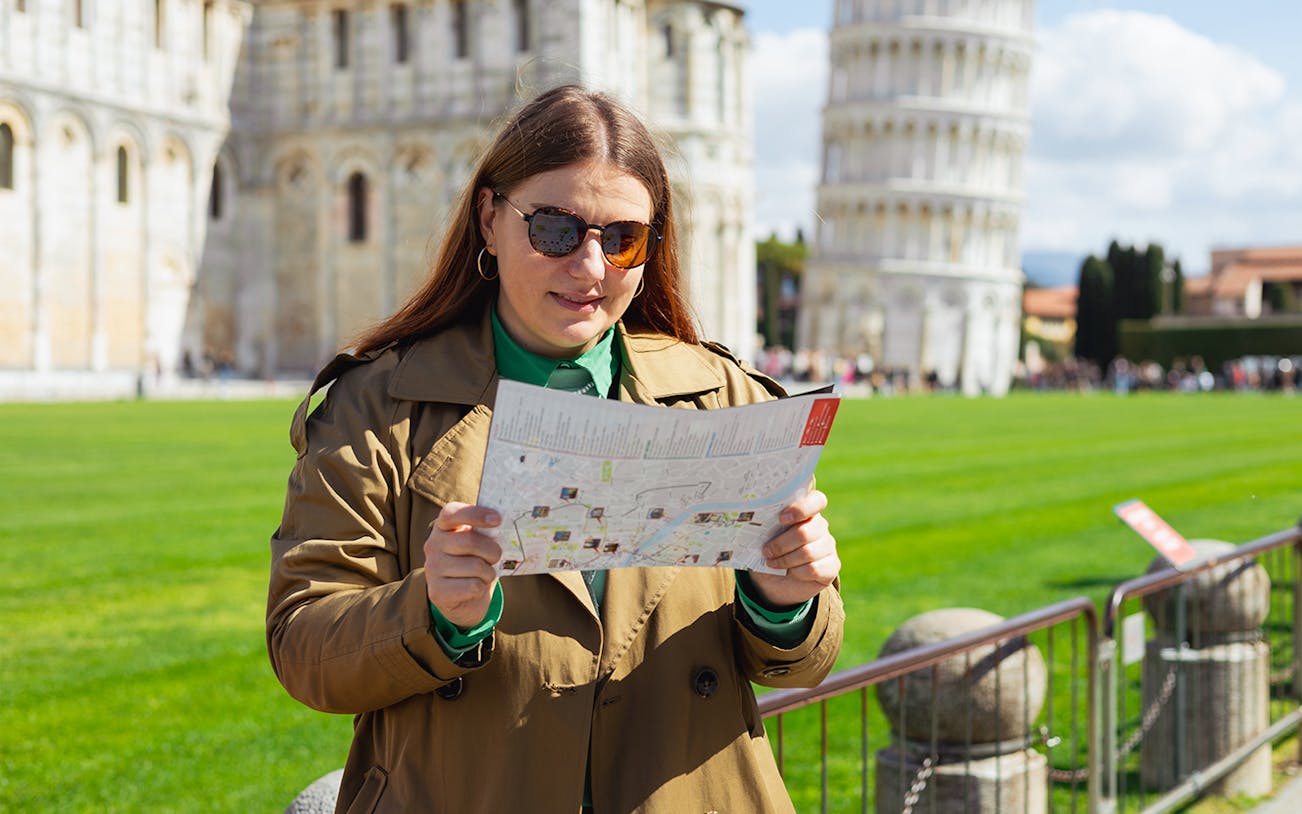 Female tour guide explaining the Leaning Tower of Pisa, Italy, to a group of tourists.