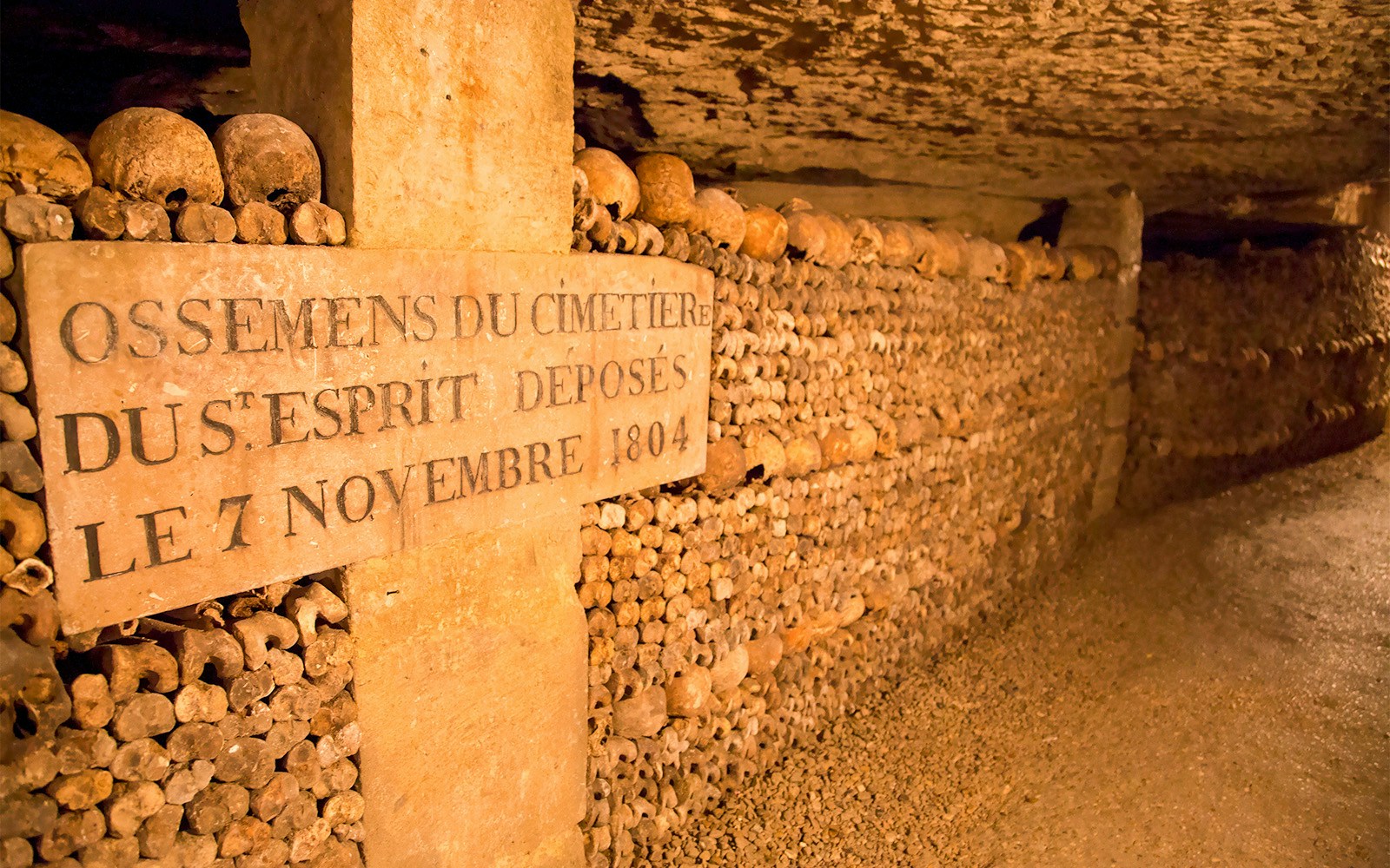 Skulls and bones stacked in the Paris Catacombs with an inscription dated 1804.