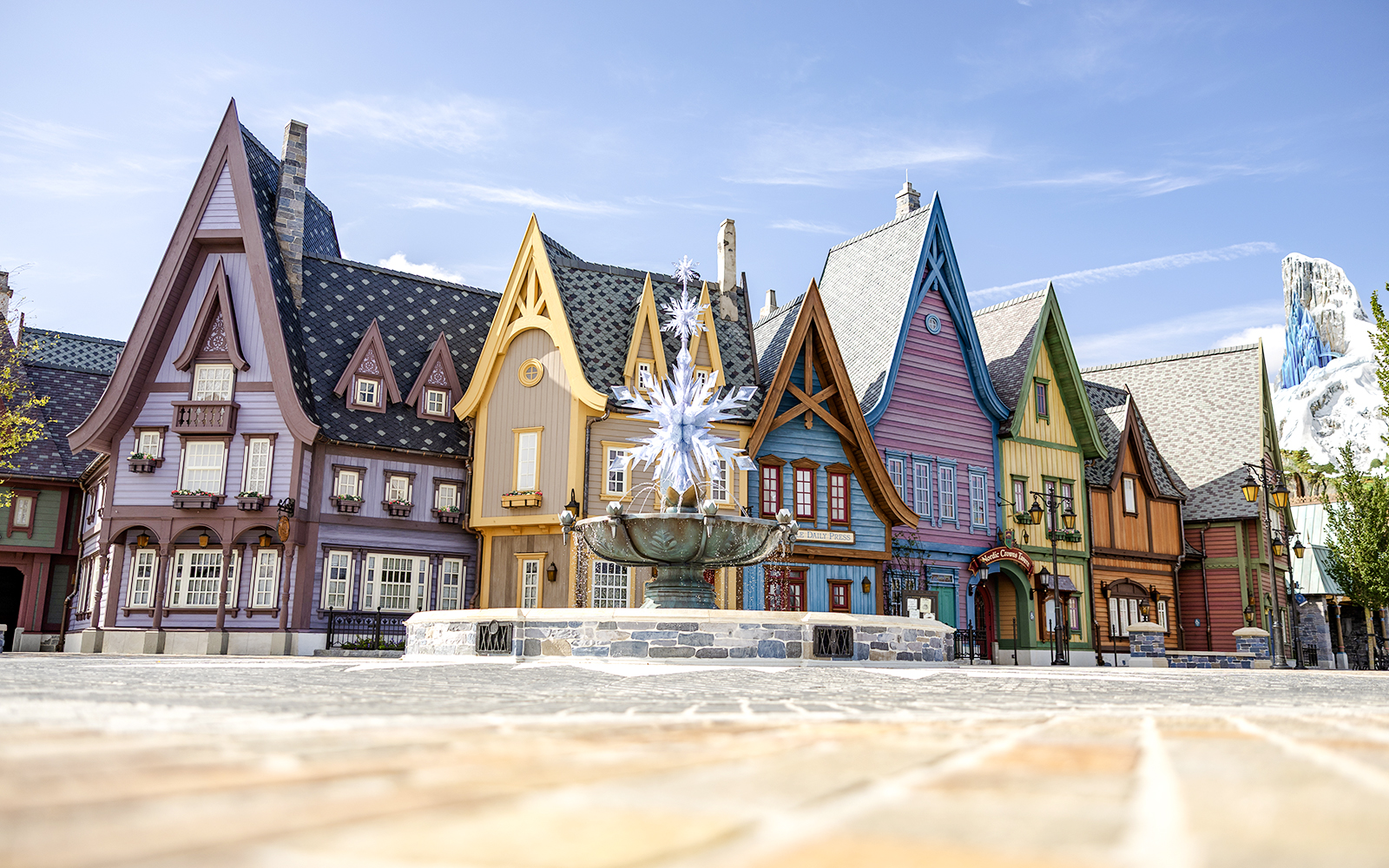 Colorful Arendelle village buildings with snowflake fountain at Disneyland World of Frozen.