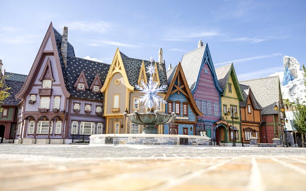 Colorful Arendelle village buildings with snowflake fountain at Disneyland World of Frozen.