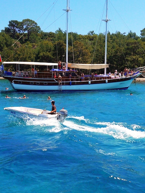 Boat tour near Phaselis with people swimming, Antalya coast in the background.
