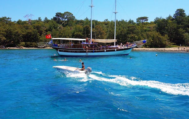 Boat tour near Phaselis with people swimming, Antalya coast in the background.