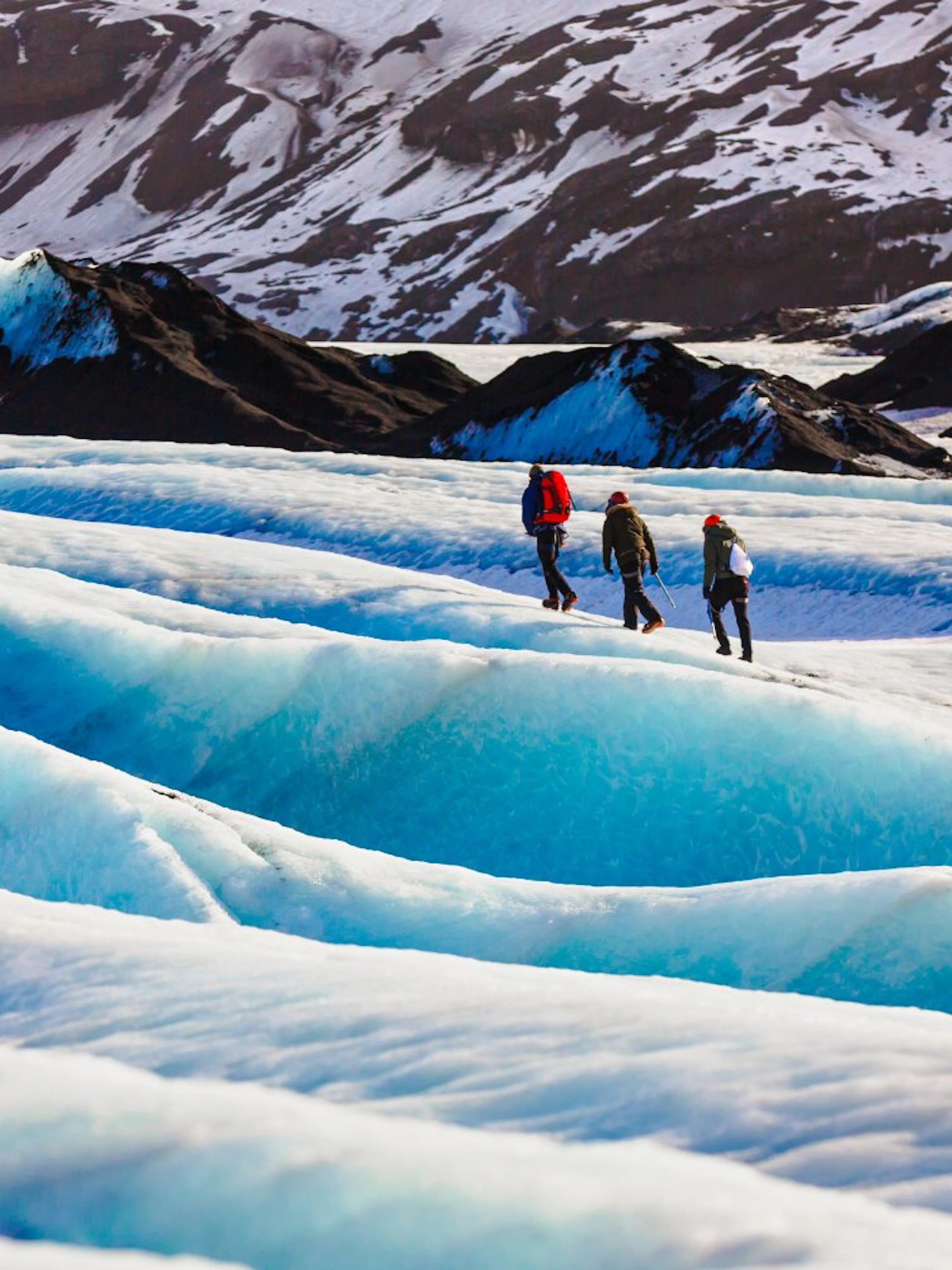 Guide and hikers walking on Solheimajokull glacier in Iceland.