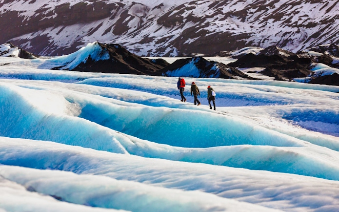 Guide and hikers walking on Solheimajokull glacier in Iceland.